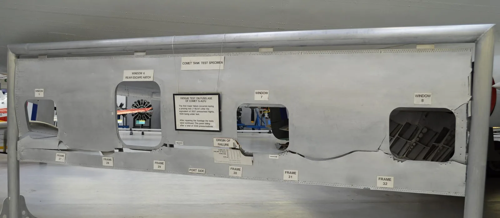 Painel de fuselagem do Comet G-ALYU exposto no RAF Museum Cosford, com os recortes das janelas e a rasgadura da falha por fadiga.