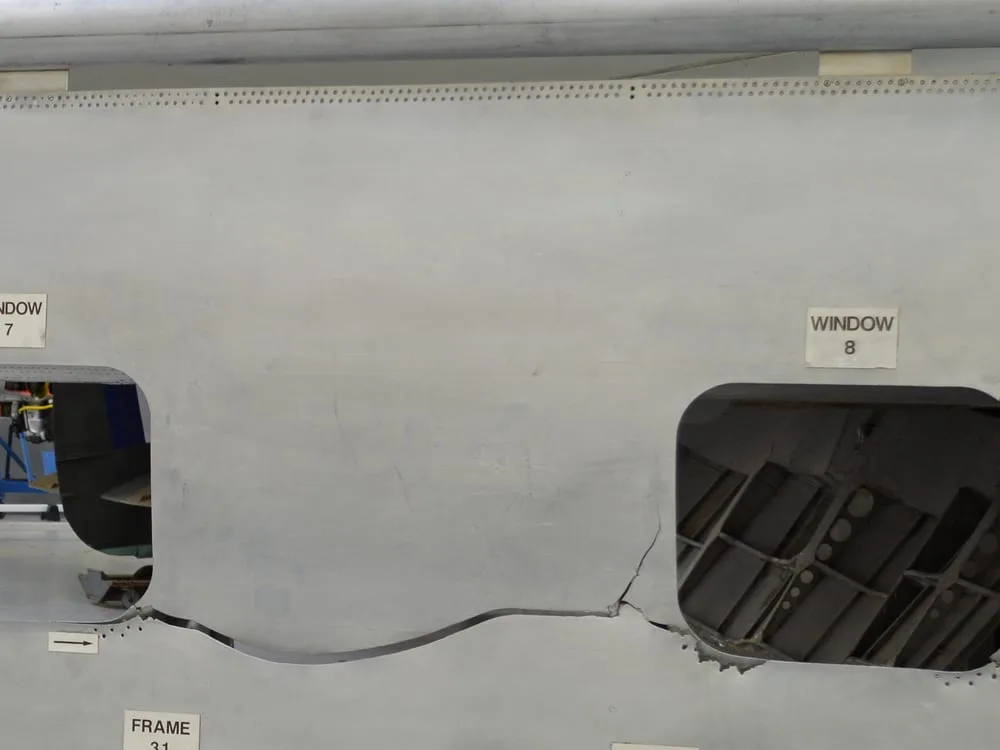 Detalhe do painel de ensaio do G-ALYU: a chapa rasgada entre os recortes das janelas 7 e 8.